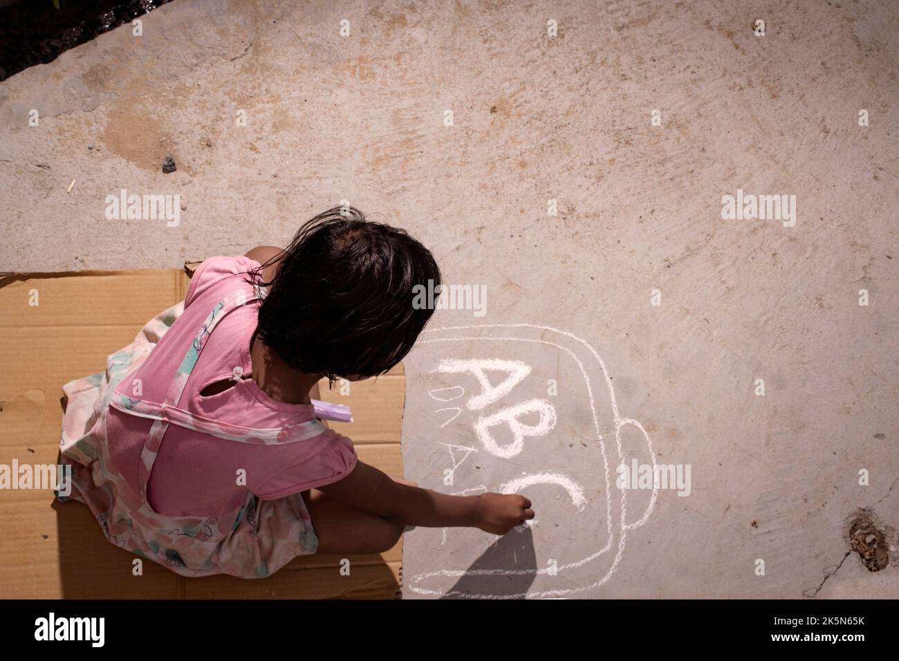 povero bambino che studia e scrive su strada con gesso in assenza di libri Foto Stock