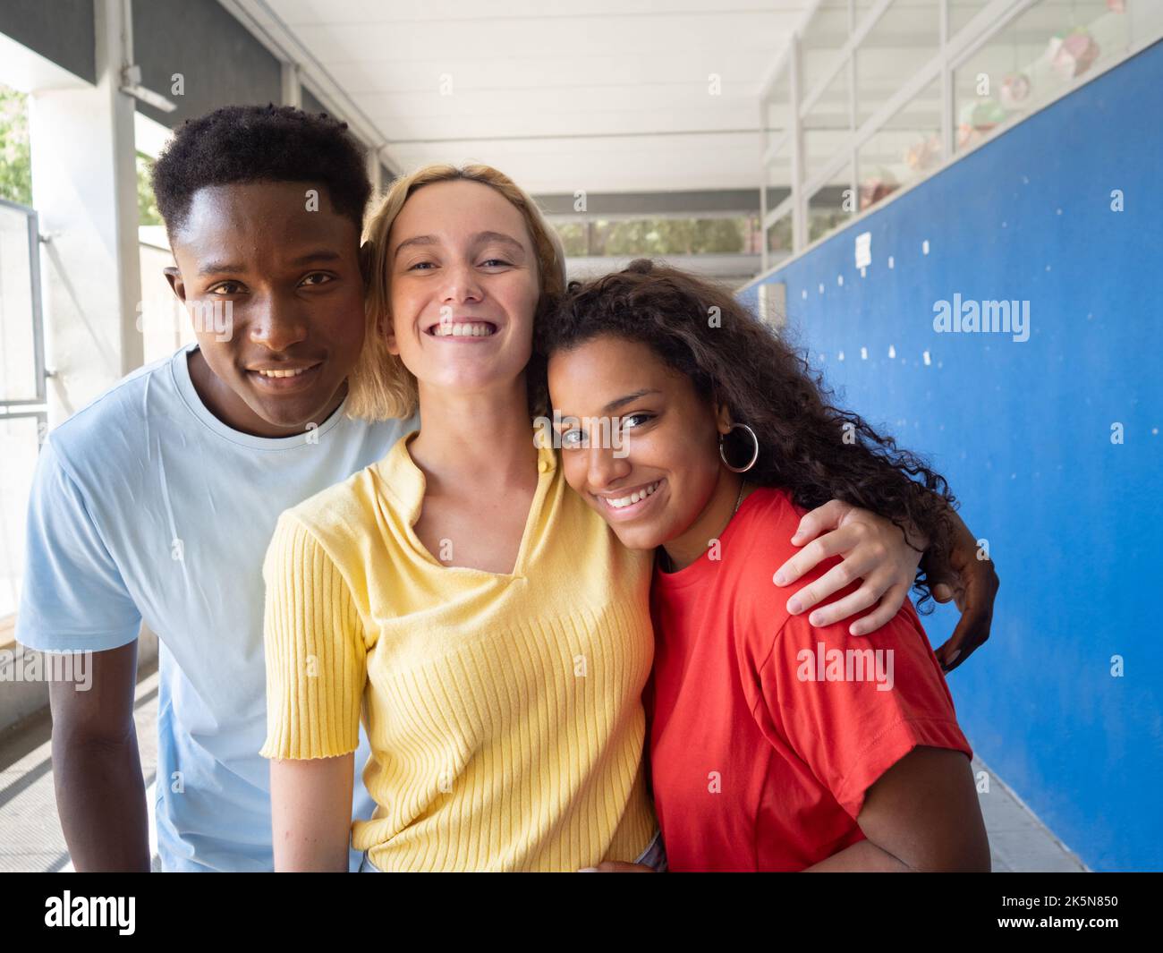 Tre giovani amici millenari multietnici che guardano ridere la fotocamera. Diversità, studenti Foto Stock