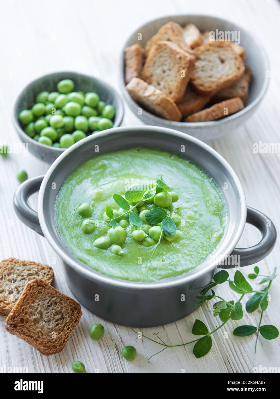 Ciotola per zuppa di piselli freschi e verdi su sfondo di cemento grigio Foto Stock