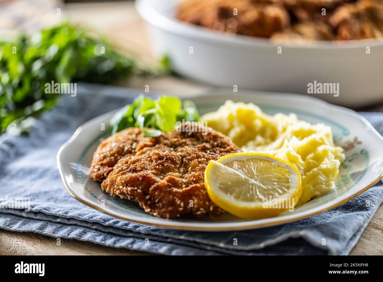Carne impanata servita con purè di patate, fettina di limone e verdure. Foto Stock