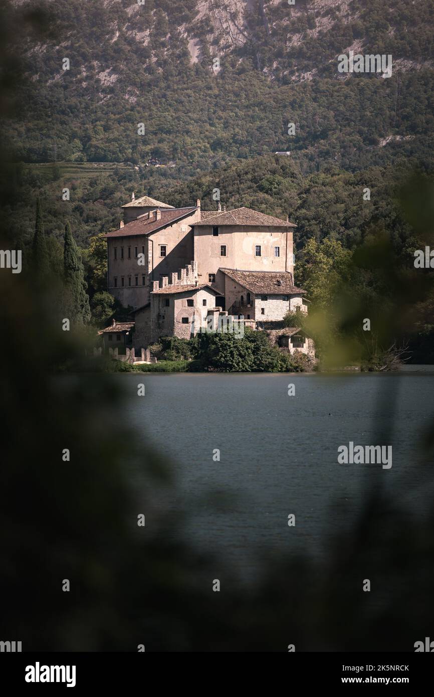 Uno scatto verticale di un antico castello circondato da montagne sempreverdi con un lago in primo piano Foto Stock