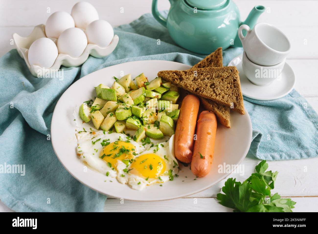 Colazione continentale europea a base di uova con salsicce, pane di segale tostato e zucchine a cubetti Foto Stock
