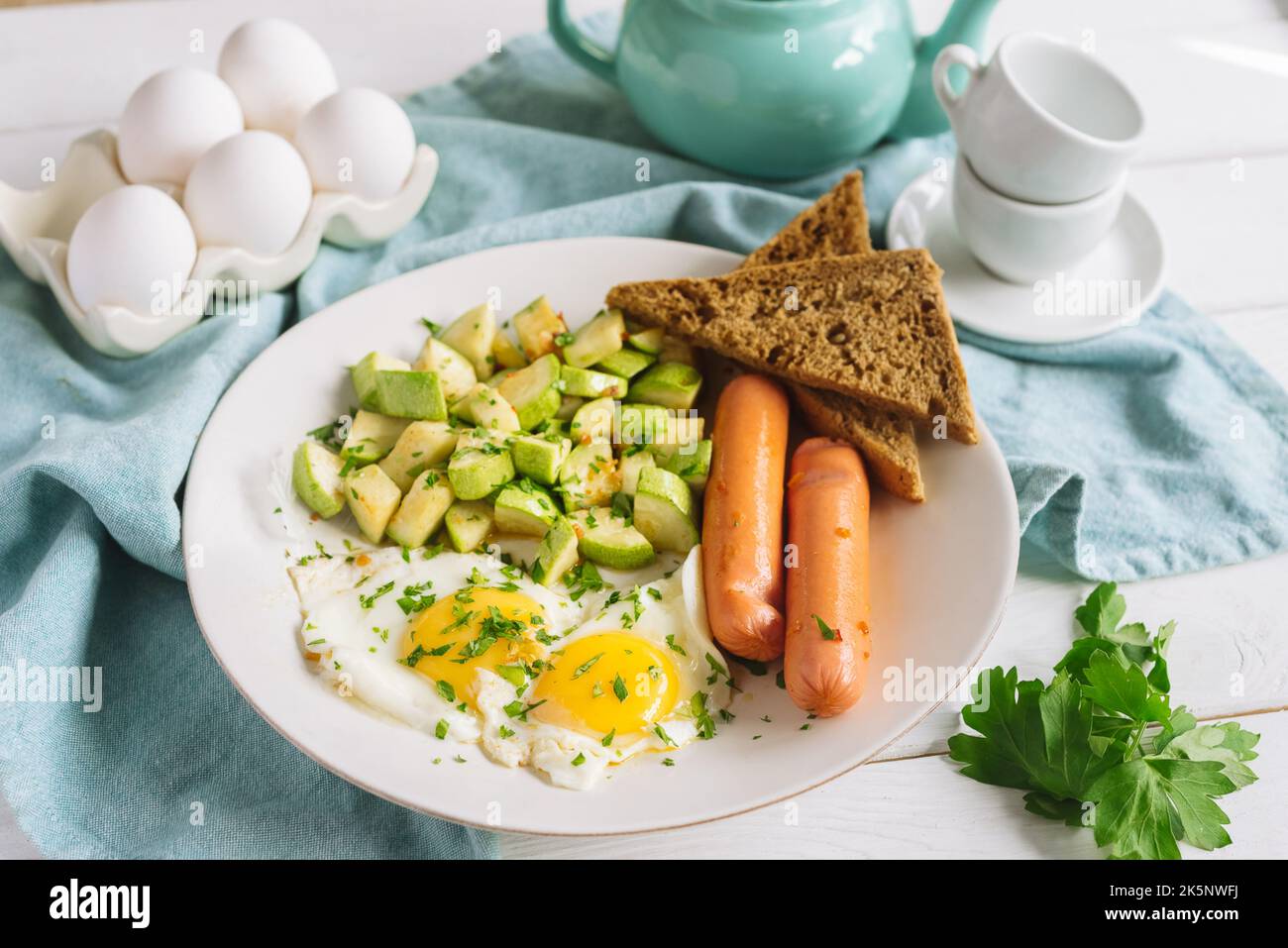 Colazione continentale europea a base di uova con salsicce, pane di segale tostato e zucchine a cubetti Foto Stock