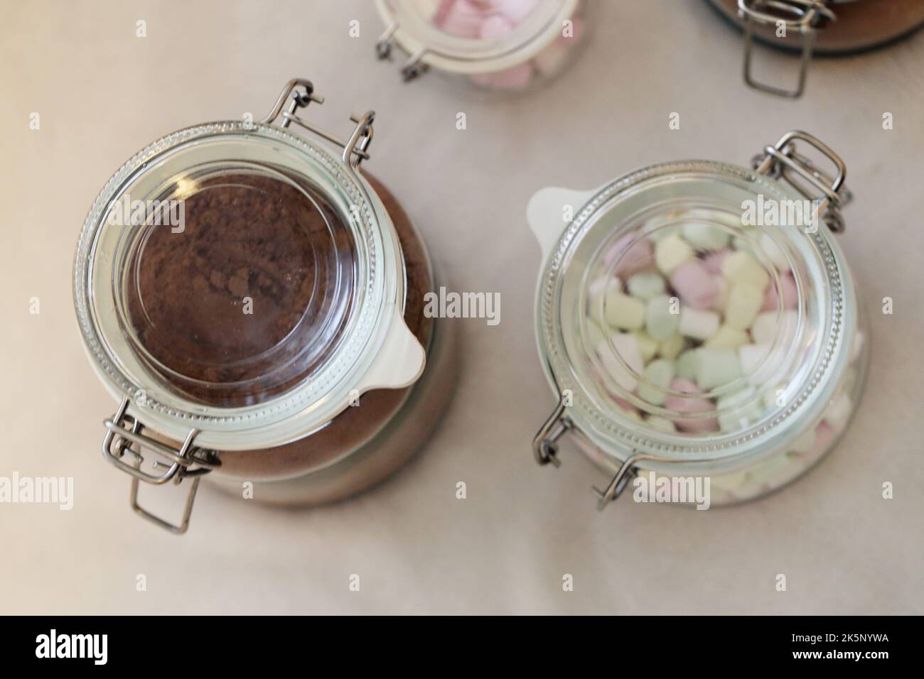 Regalo di Natale casalingo commestibile - vasetti di vetro ripieni di cacao in polvere speziato e mini marshmallows per cioccolata calda. Un regalo perfetto per il luogo! Foto Stock