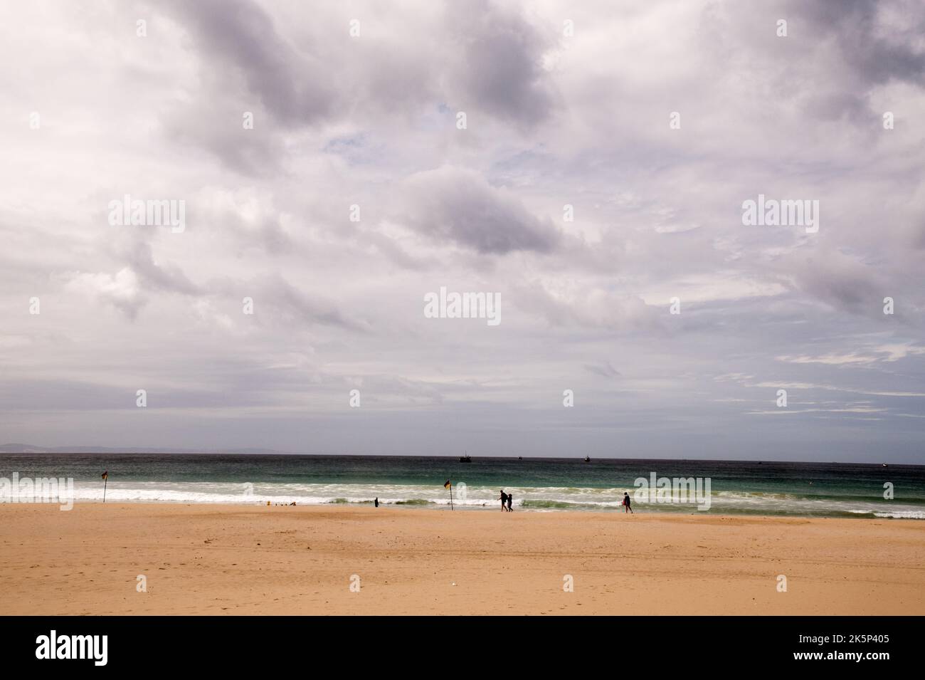 Moody e Angry nuvole su una spiaggia con la pioggia minaccia di scendere. Sabbia incontaminata e fitte nuvole Foto Stock