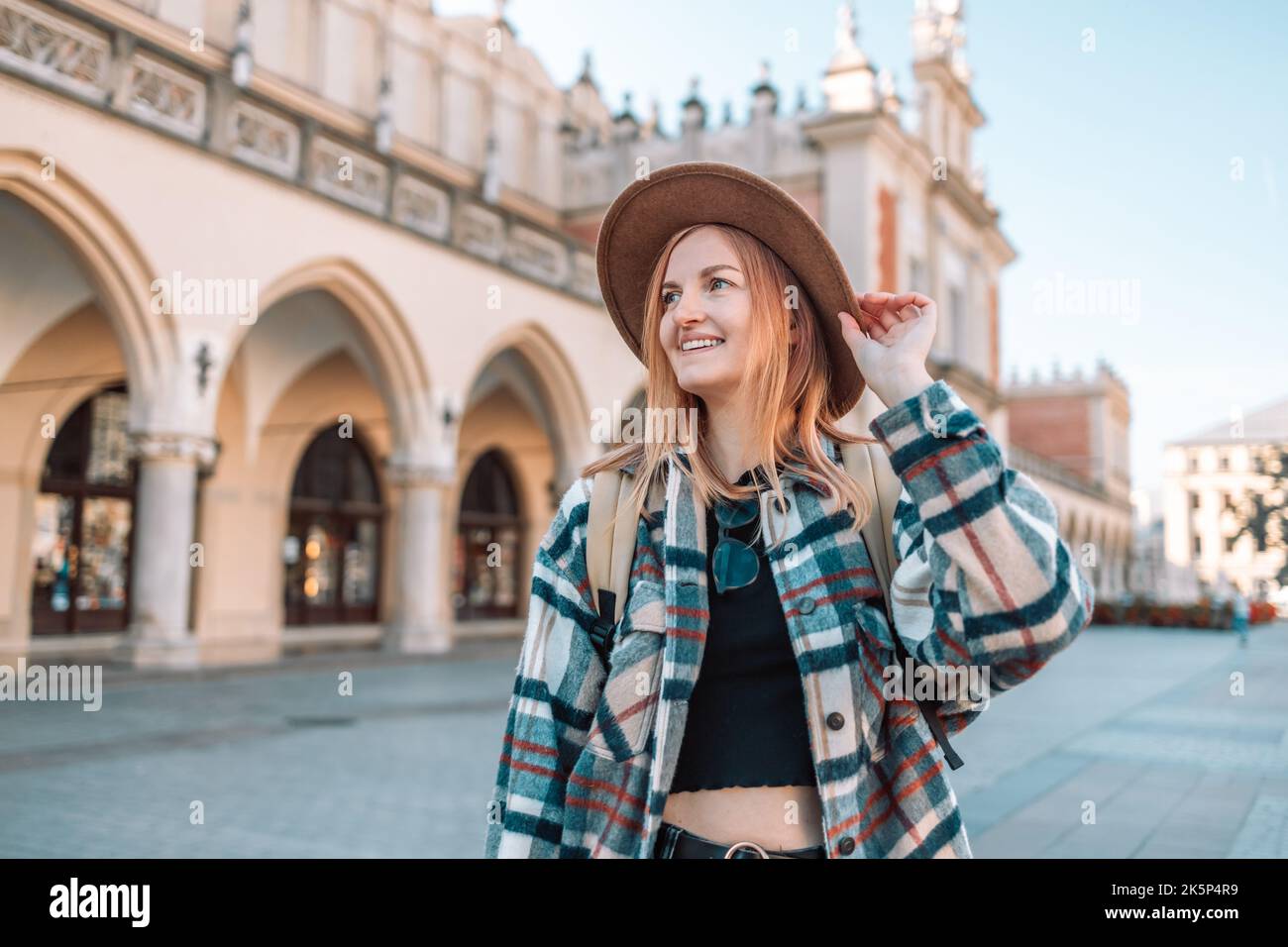 Donna giovane viaggiatore sorridere con zaino nella piazza del mercato della città vecchia a Cracovia, Polonia Foto Stock