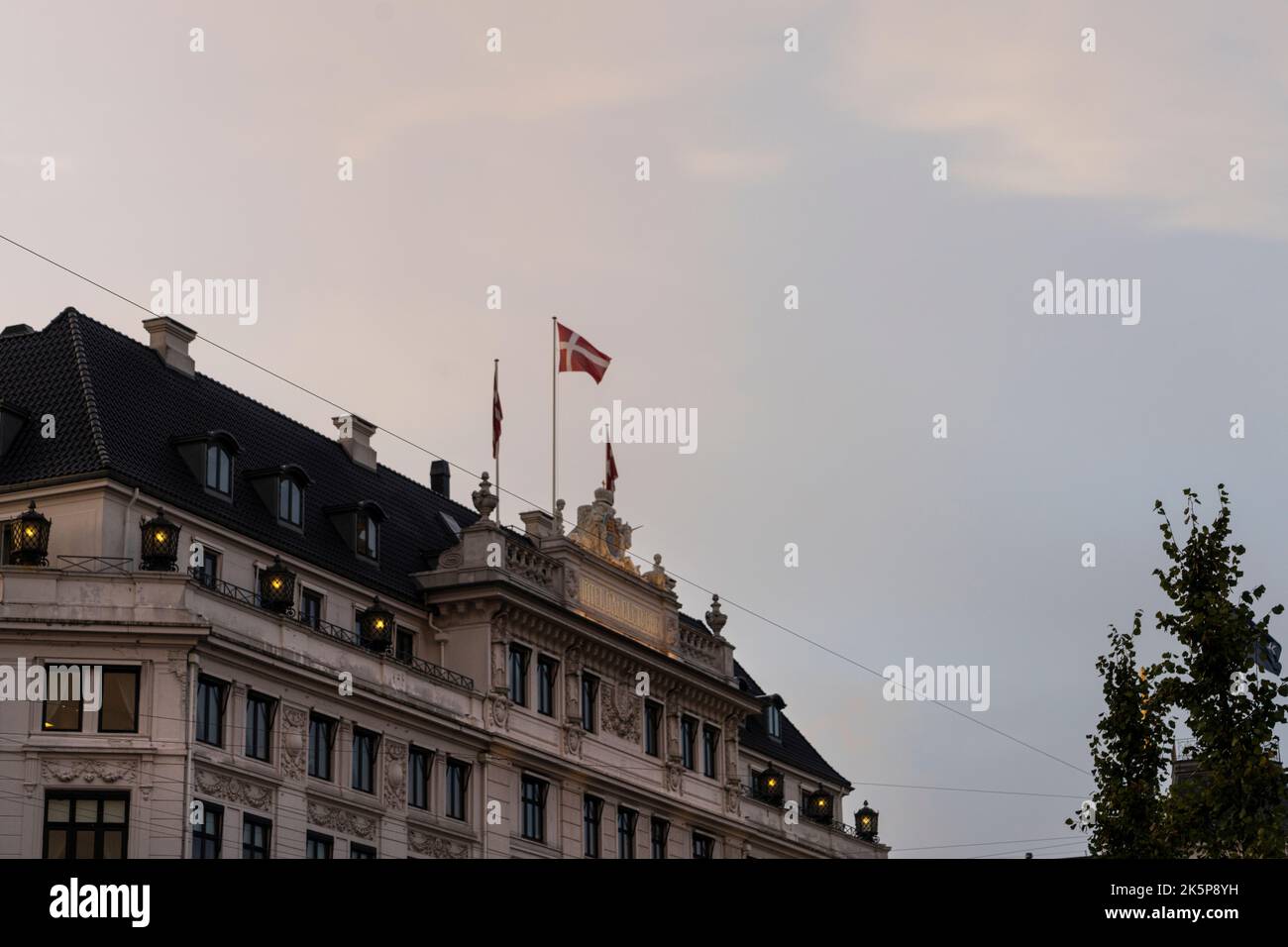 Copenaghen, Danimarca. Ottobre 2022. La bandiera danese che vola sul tetto di un antico palazzo nel centro della città Foto Stock