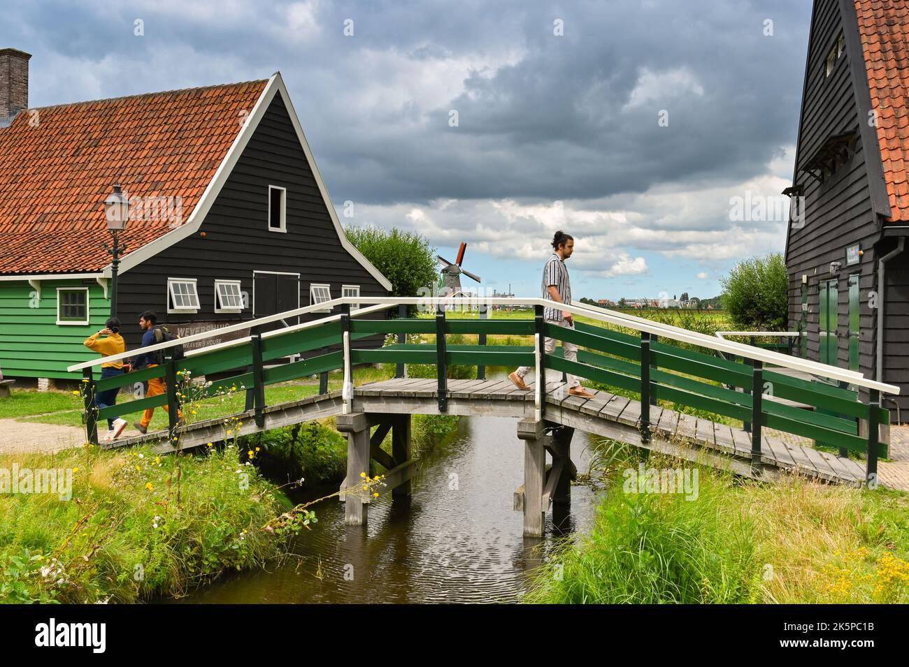 Zaandam, Paesi Bassi - 2022 agosto: Persona che cammina attraverso uno dei ponti di legno nel quartiere residenziale preservato di Zaanse Schans Foto Stock