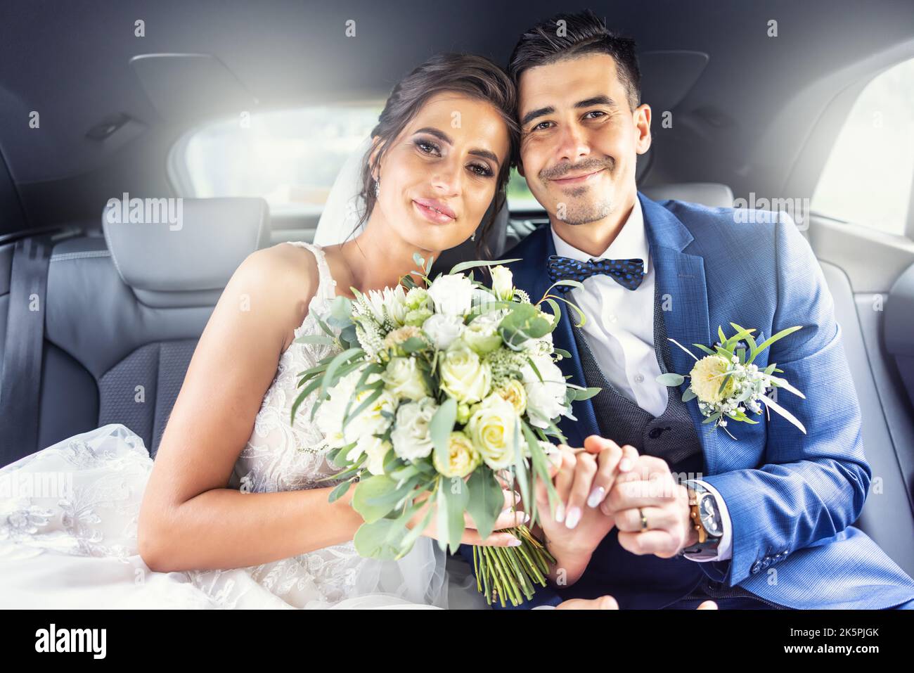 Sposi novelli felici buon-osservanti stanno sedendosi in un automobile insieme dopo aver detto thei i dos. Foto Stock