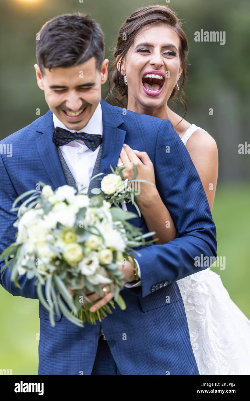 Appena sposato marito e moglie stanno avendo una risata all'aperto in un abbraccio. Foto Stock