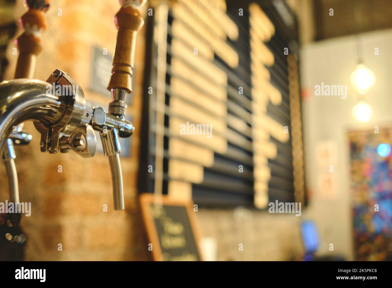 Fila di birre alla spina in un bar. La birra si tap di fila in prospettiva. Primo piano della birra Tap. Messa a fuoco selettiva. Foto Stock