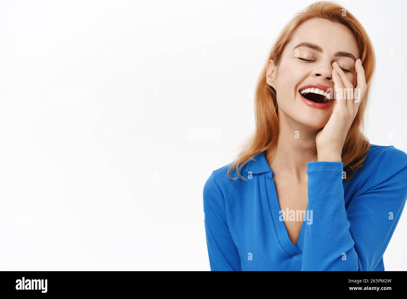 Benessere delle donne. Primo piano ritratto di donna felice ridente, tocca il suo volto chiaro, nutrito naturale, sorridente sincero, si erge su sfondo bianco Foto Stock