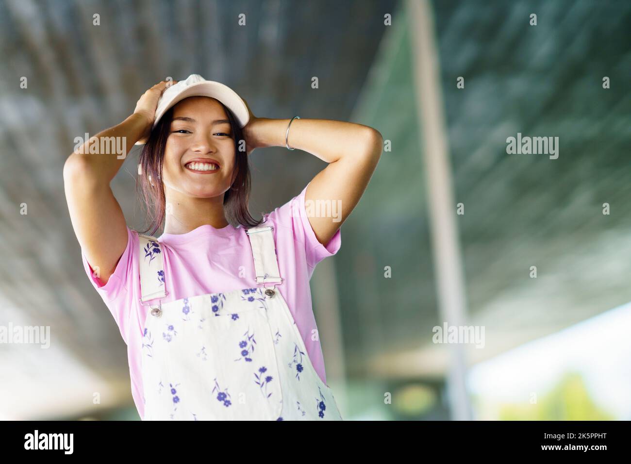 La macchina fotografica del viso della giovane donna adorabile che sorride  mentre prova una fascia carina nel negozio di accessori. bello acquisto  femminile cinese asiatico nel venditore del negozio. donna affascinante che