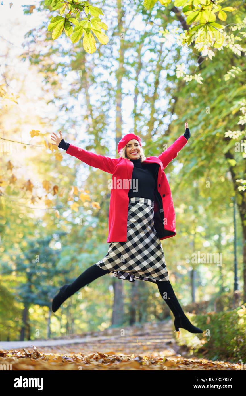Donna alla moda che salta felicemente nel parco autunnale Foto Stock