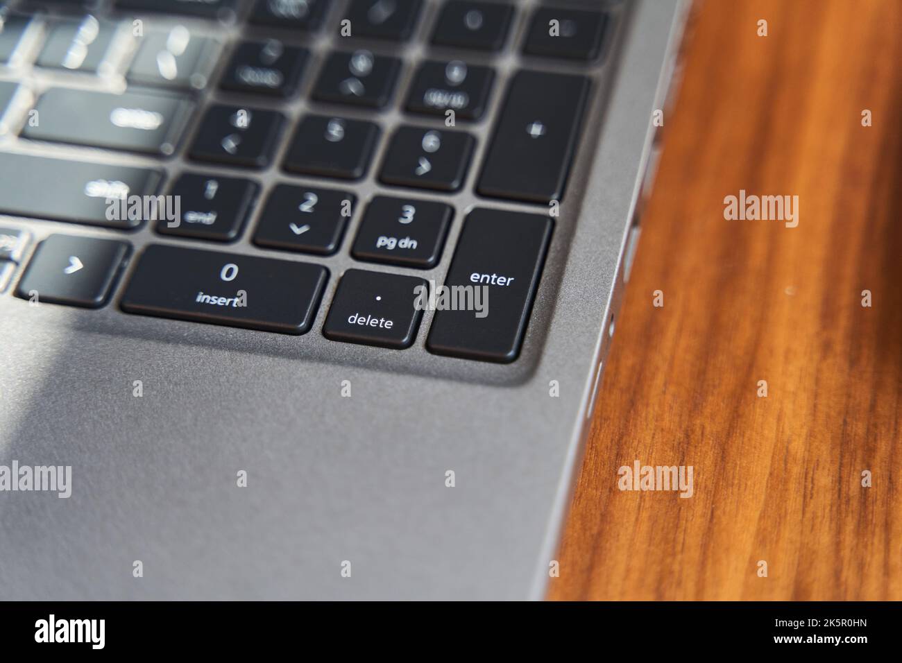 Vista dall'alto di una parte della tastiera grigia di un computer portatile su un tavolo di legno Foto Stock