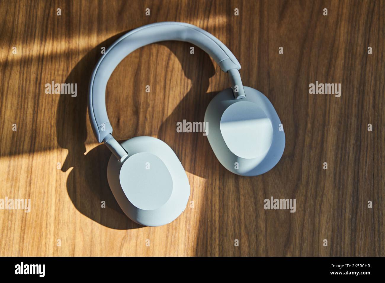 Vista dall'alto delle grandi cuffie wireless bianche appoggiate su un tavolo di legno Foto Stock