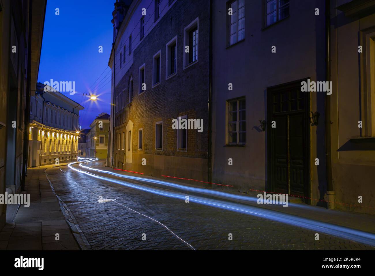 Strada e pista luminosa dalla macchina di notte nel centro storico di Vilnius, Lituania Foto Stock