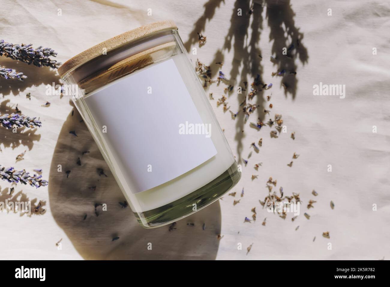 Etichetta candela mock-up. Lavanda secca e candela di vetro con etichetta vuota alla luce naturale del sole Foto Stock