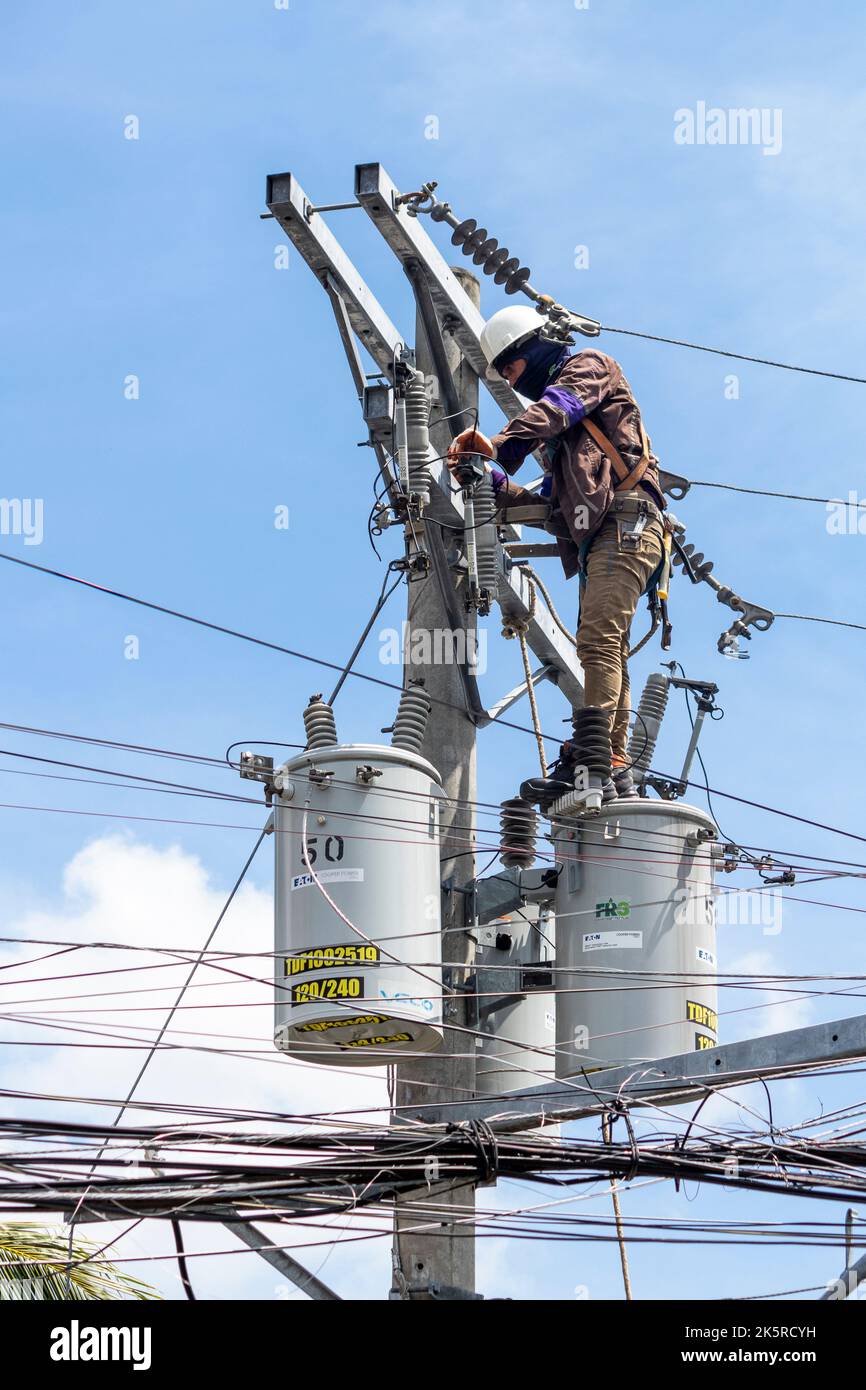 Un uomo di linea di una società elettrica che lavora su un polo elettrico a Cebu City, Filippine Foto Stock