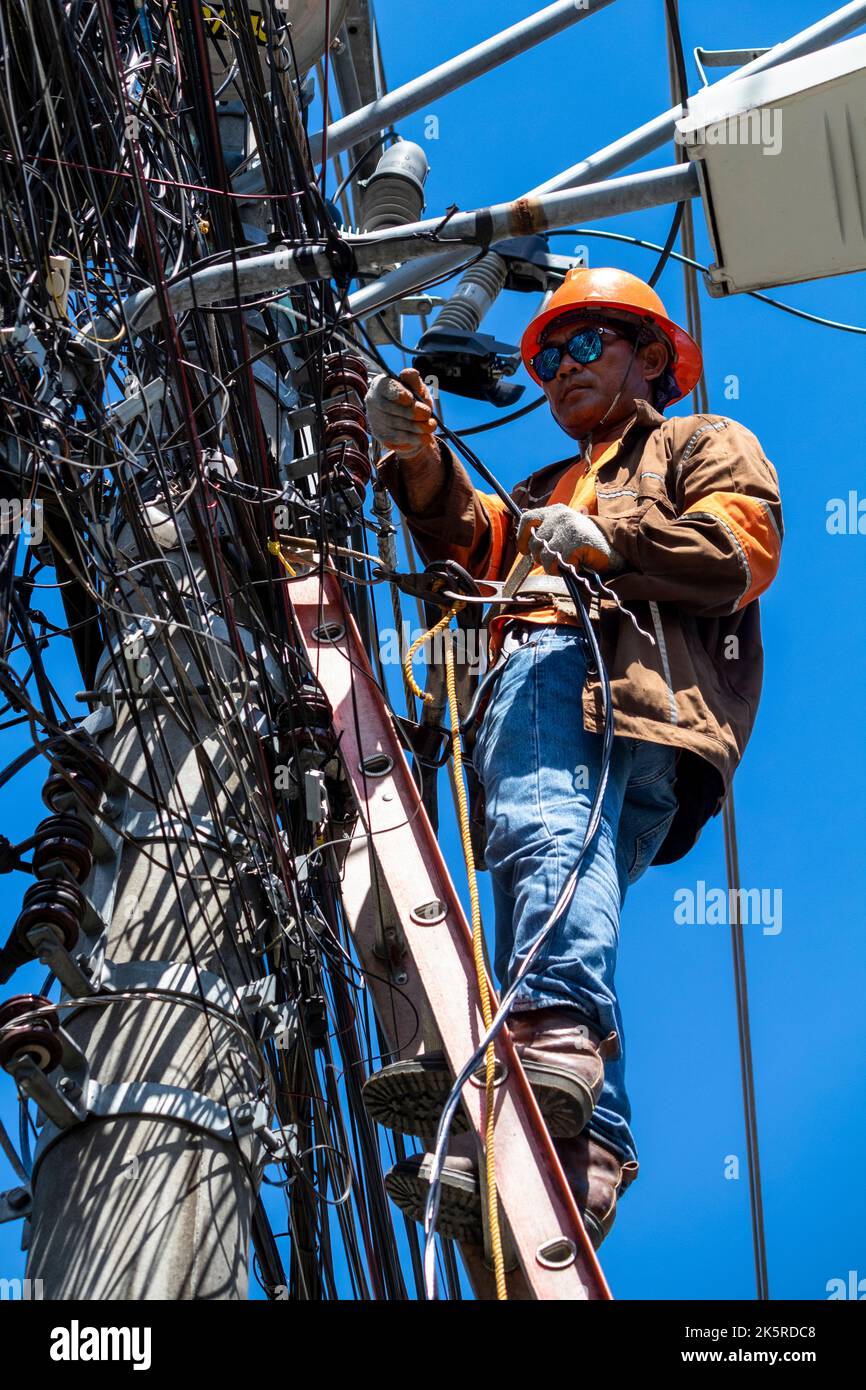 Un uomo di linea di una società elettrica che lavora su un polo elettrico a Cebu City, Filippine Foto Stock