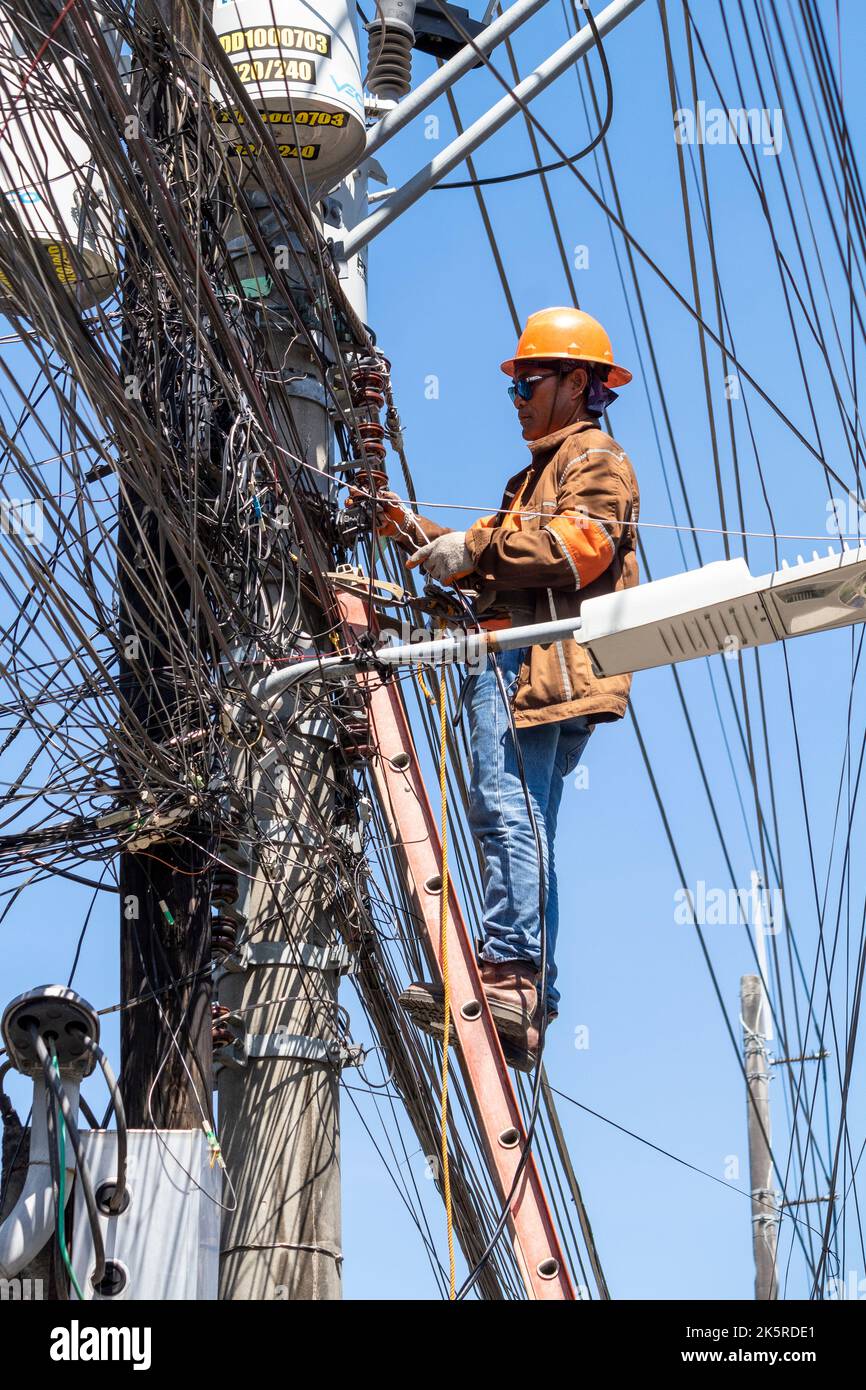 Un uomo di linea di una società elettrica che lavora su un polo elettrico a Cebu City, Filippine Foto Stock