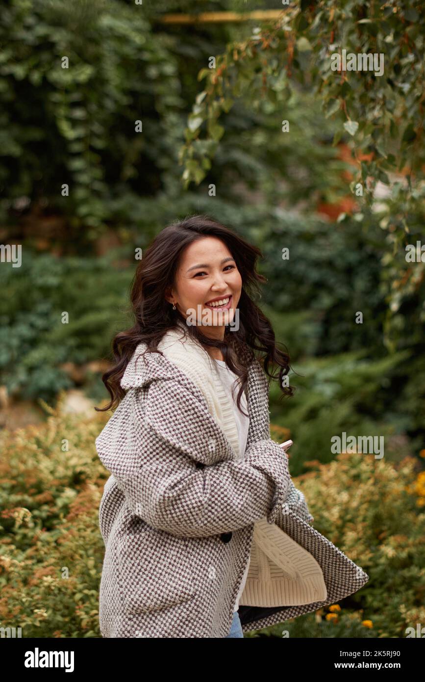 Ritratto di bella donna asiatica kazako brunette con un sorriso affascinante camminando all'aperto Foto Stock