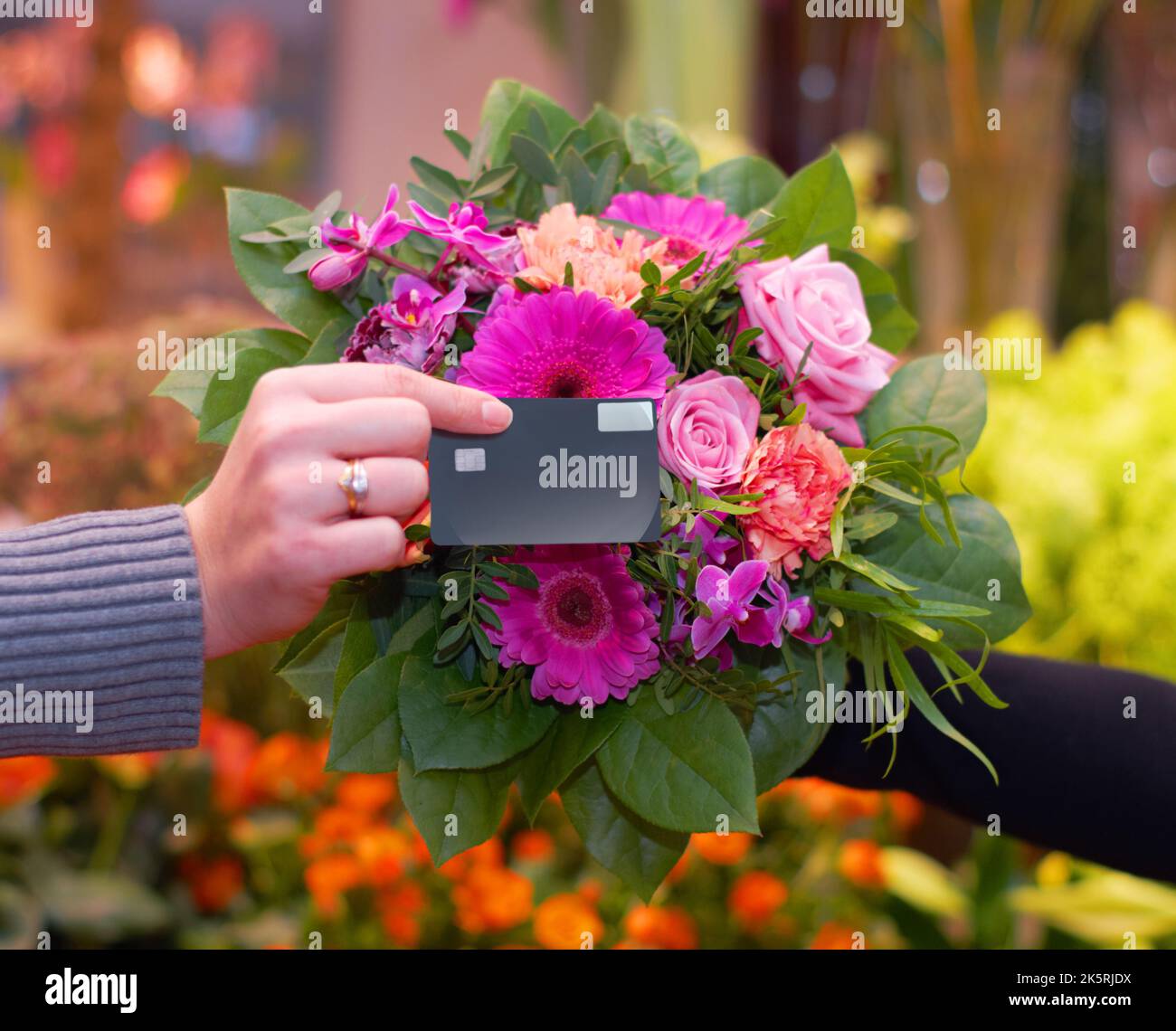 Acquisto dei fiori viola. Una donna che compra i fiori con la sua carta di credito da un fiorista. Foto Stock