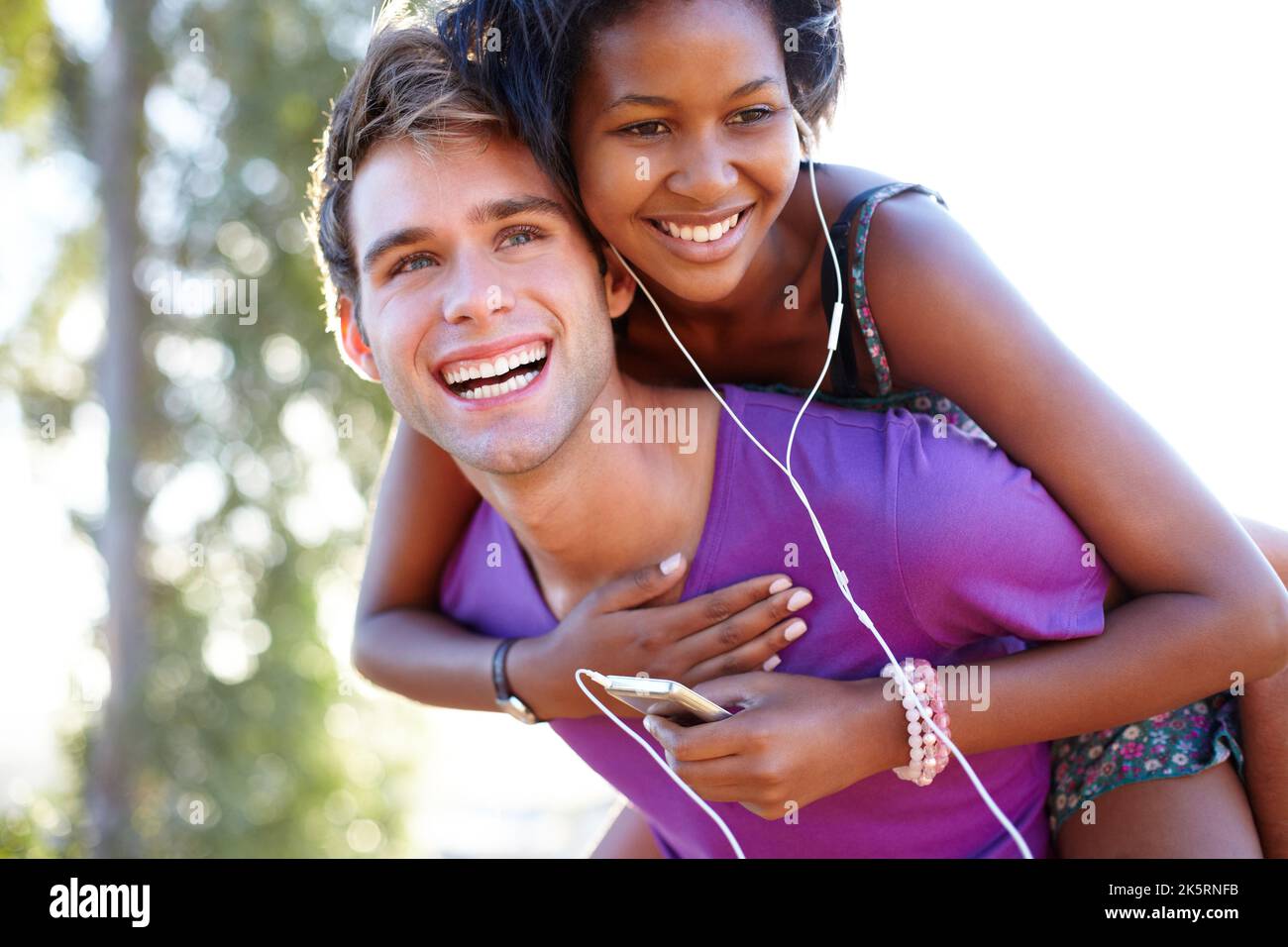 Questa è la colonna sonora della nostra vita. Giovane uomo che dà al suo amico un giro di piggyback mentre ascolta la musica. Foto Stock