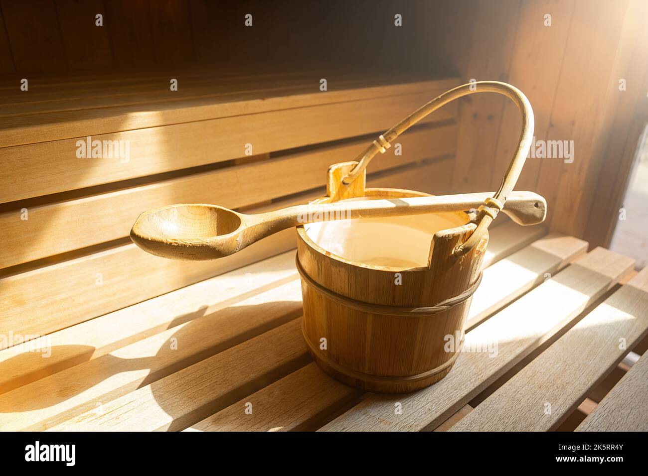 Secchio d'acqua con cucchiaio di legno per versare acqua su pietre calde nella sauna finlandese, spa e bagno termale a temperatura calda immagine concettuale. Foto Stock