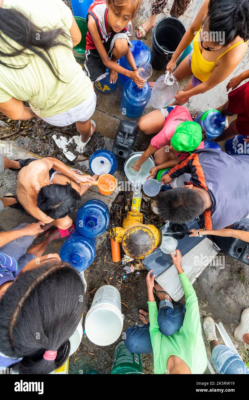 La gente ottiene l'acqua da un idrante dovuto una scarsità di acqua portata da Typhoon Odette a Cebu City, Filippine Foto Stock