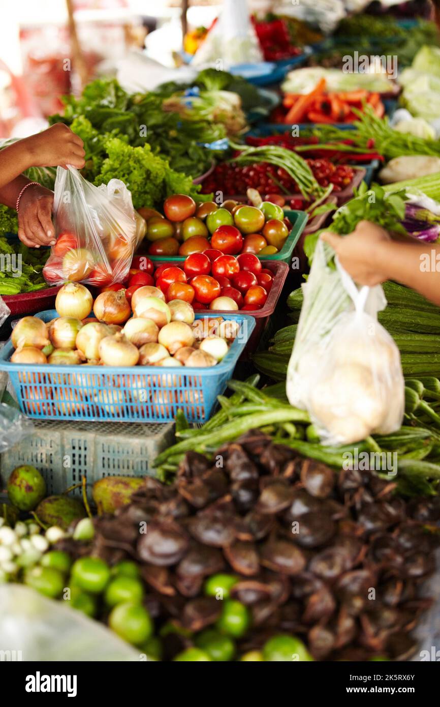 Mantenere vivo il commercio locale. Un cliente che acquista verdura in un mercato locale tailandese. Foto Stock