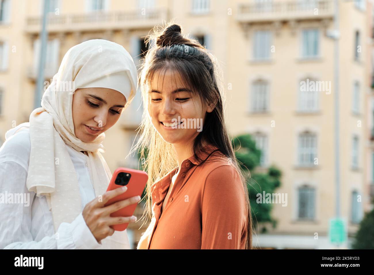 Giovani amici multietnici che usano il telefono cellulare insieme all'aperto per strada. Foto Stock