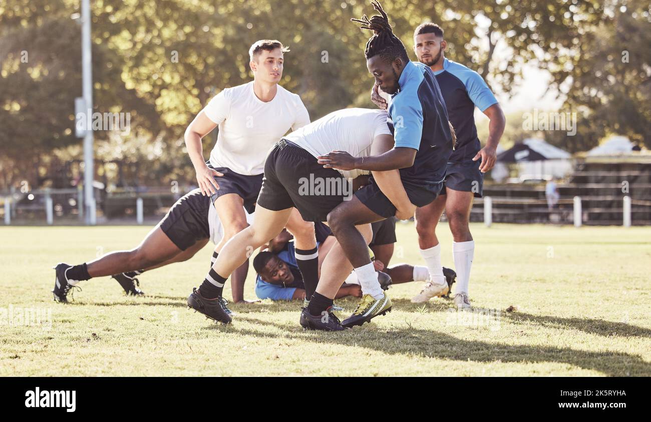 Giocatore di rugby caucasico che tenta di affrontare un avversario durante una partita di rugby fuori sul campo. Giovane atletico che affronta un avversario in un Foto Stock