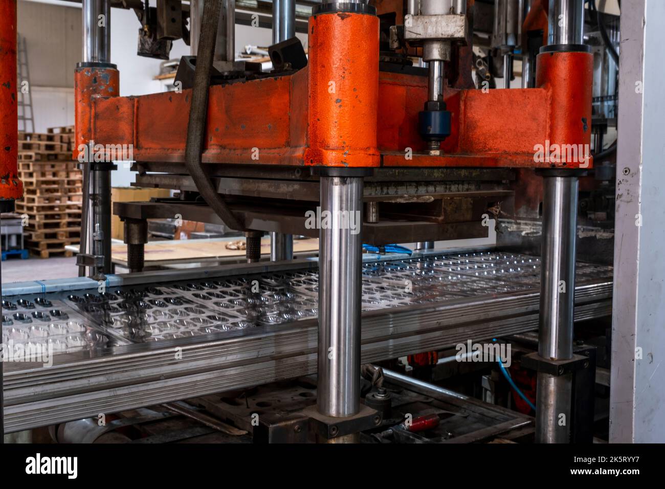 Termoformatrice sottovuoto in fabbrica, la termoformatrice sottovuoto viene utilizzata per la produzione di imballaggi in plastica. Primo piano della macchina che fa un mol Foto Stock