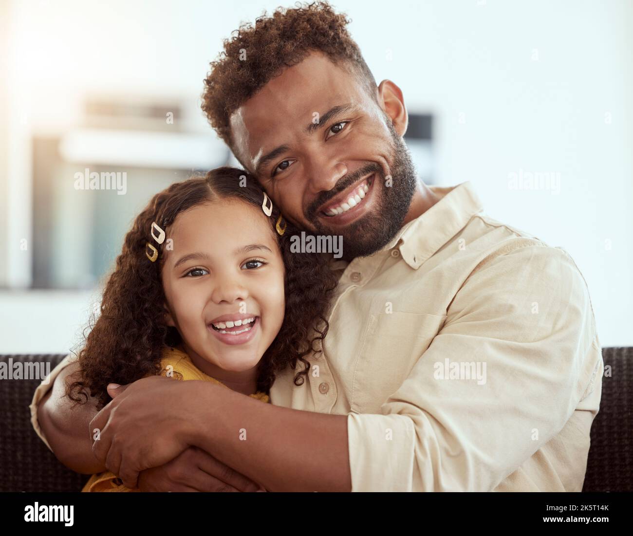Ritratto di razza mista singolo padre e figlia abbracciando nel salotto di casa. Ragazza ispanica sorridente abbracciando e legandosi con un singolo genitore dentro Foto Stock