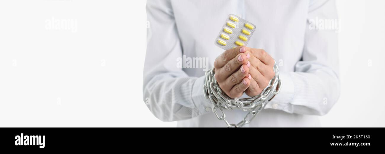La donna sta tenendo pillole con le mani legate dalla catena Foto Stock