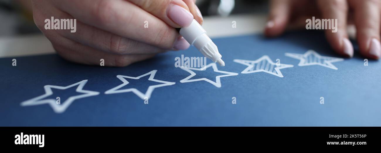 Mano femminile che incrocia le stelle di valutazione della qualità del servizio con primo piano marcatore bianco Foto Stock