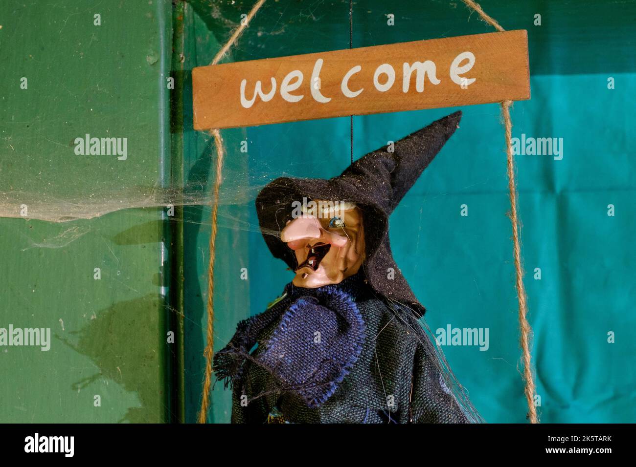 cartello di benvenuto in stile halloween con la strega in cappello a punta appeso in casa porta coperta da ragnatela Foto Stock