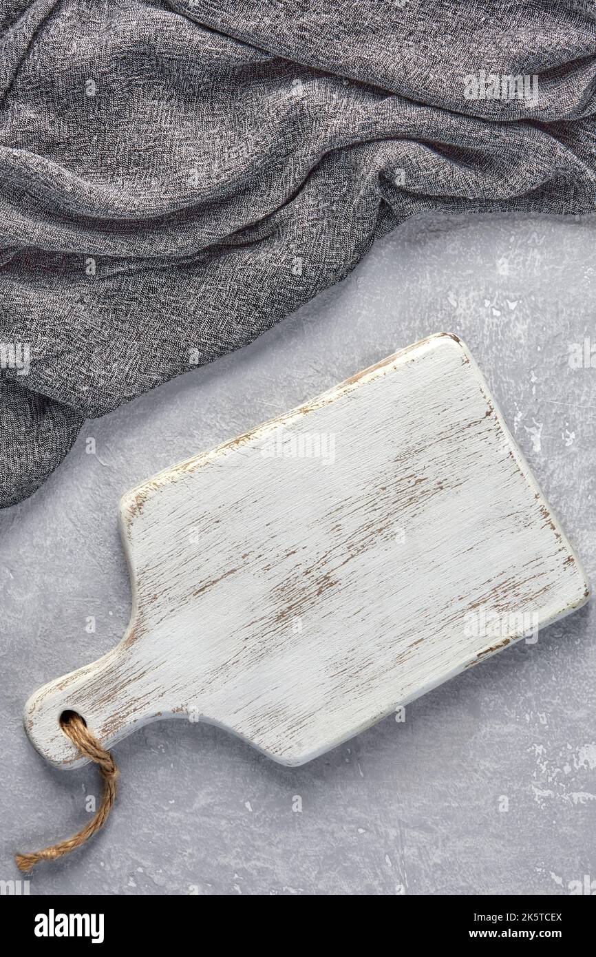 Camera di taglio in legno bianco e asciugamano da cucina grigio su un tavolo in cemento grigio chiaro Foto Stock