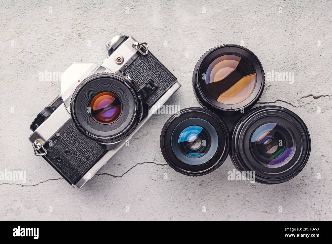 La vecchia macchina fotografica, l'obiettivo e la pellicola immagine della macchina fotografica rotolano in primo piano sullo sfondo della pietra Foto Stock