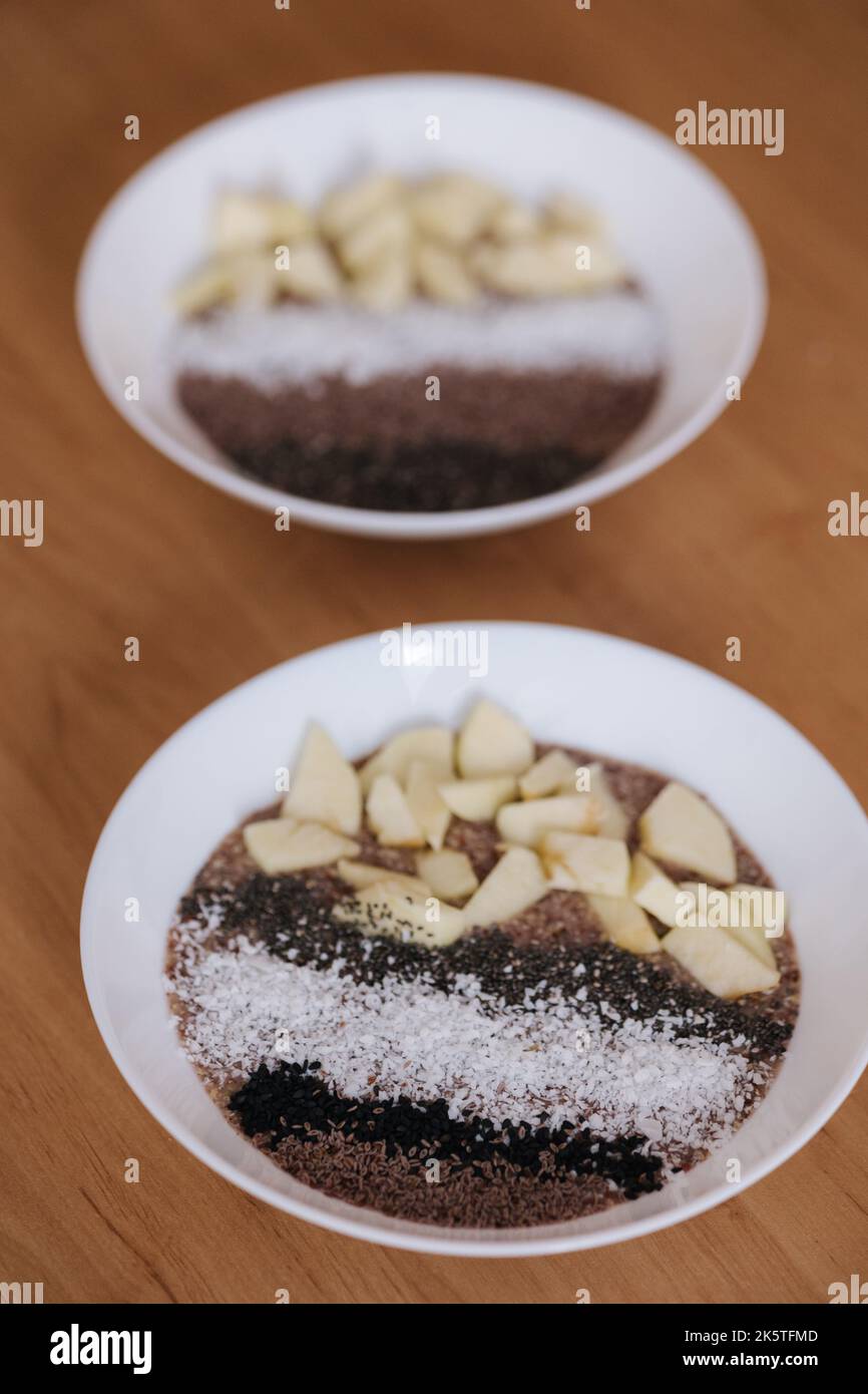 Porridge crudo vegano con frutti e chia, semi di sesamo nero e psyllium, fiocchi di cocco. Cibo sano nutriente e fresco. Due piastre Foto Stock