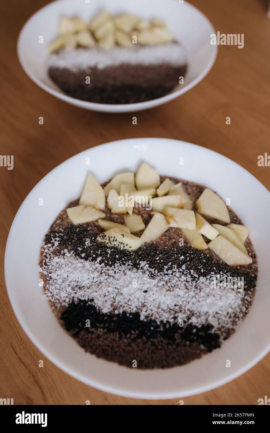 Porridge crudo vegano con frutti e chia, semi di sesamo nero e psyllium, fiocchi di cocco. Cibo sano nutriente e fresco. Due piastre Foto Stock