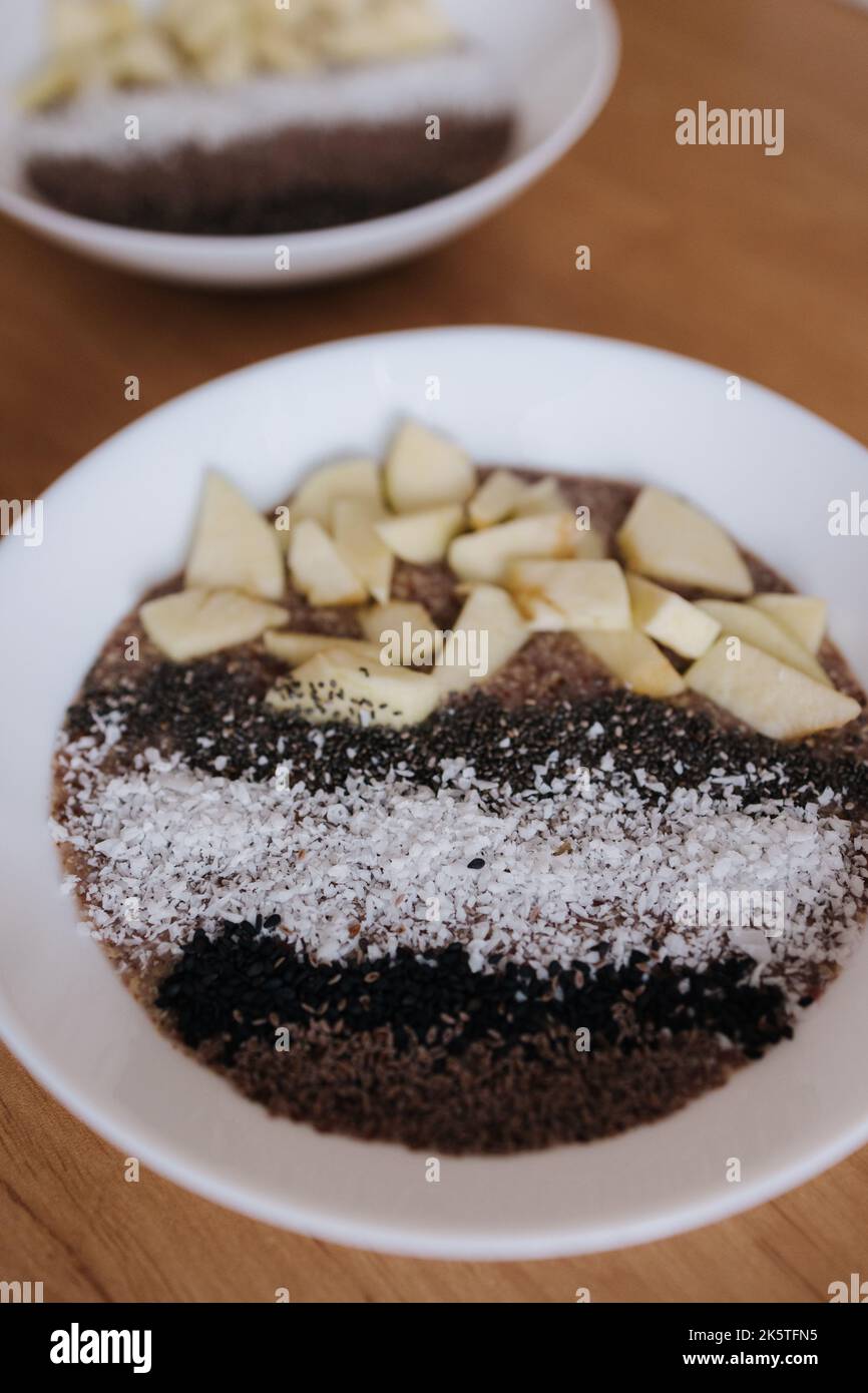 Porridge crudo vegano con frutti e chia, semi di sesamo nero e psyllium, fiocchi di cocco. Cibo sano nutriente e fresco. Due piastre Foto Stock