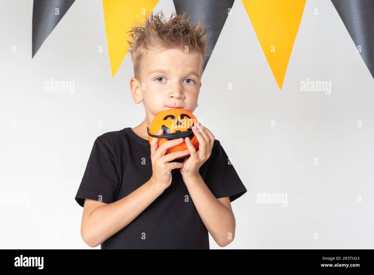 Halloween ragazzi con secchi di zucca mangiare caramella su uno sfondo bianco studio con una ghirlanda. Pronti per una vacanza trick o trick. Foto Stock