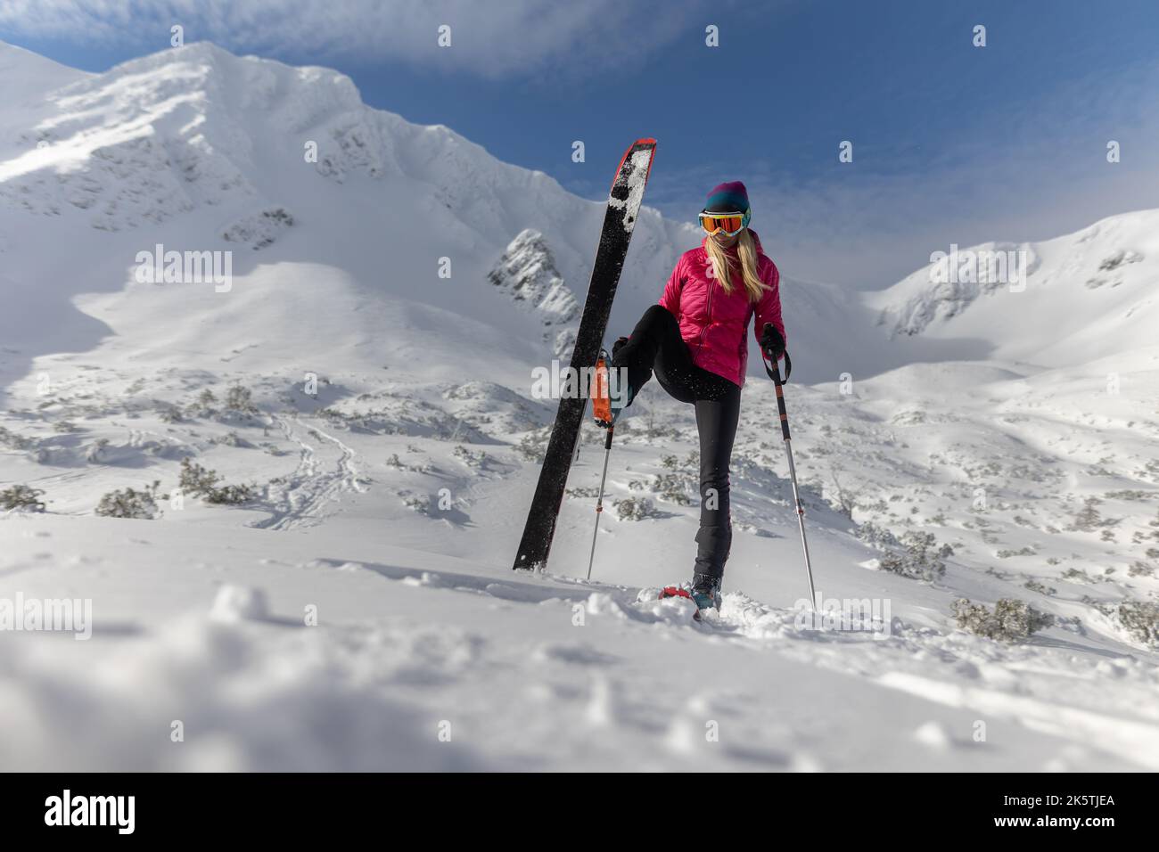 Sciatore di backcountry femminile che si sta camminando fino alla cima di una cima nevosa nei bassi Tatra in Slovacchia, guardando la macchina fotografica. Foto Stock