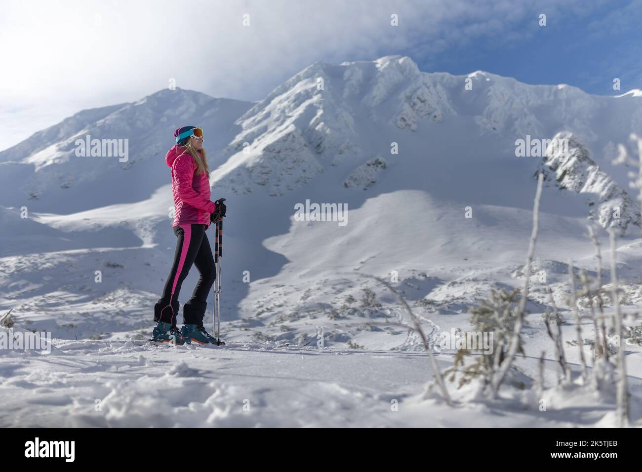 Sciatore di backcountry femminile che si sta camminando fino alla cima di una cima nevosa nei bassi Tatra in Slovacchia, guardando la macchina fotografica. Foto Stock