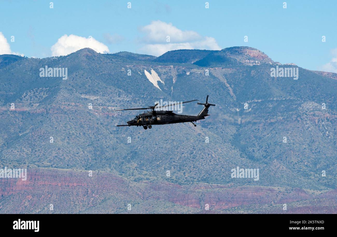 Un solo elicottero dell'esercito che vola con una montagna sullo sfondo Foto Stock