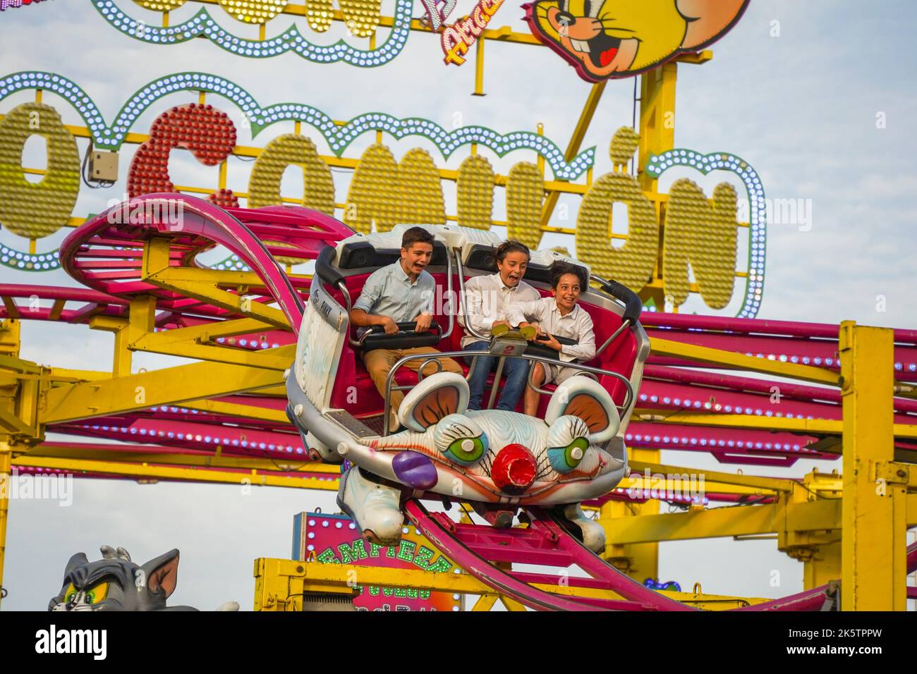 Tre adolescenti sul punto più alto, spaventato nel giro in macchina delle montagne russe sulla fiera annuale. Funfair. Spagna. Foto Stock