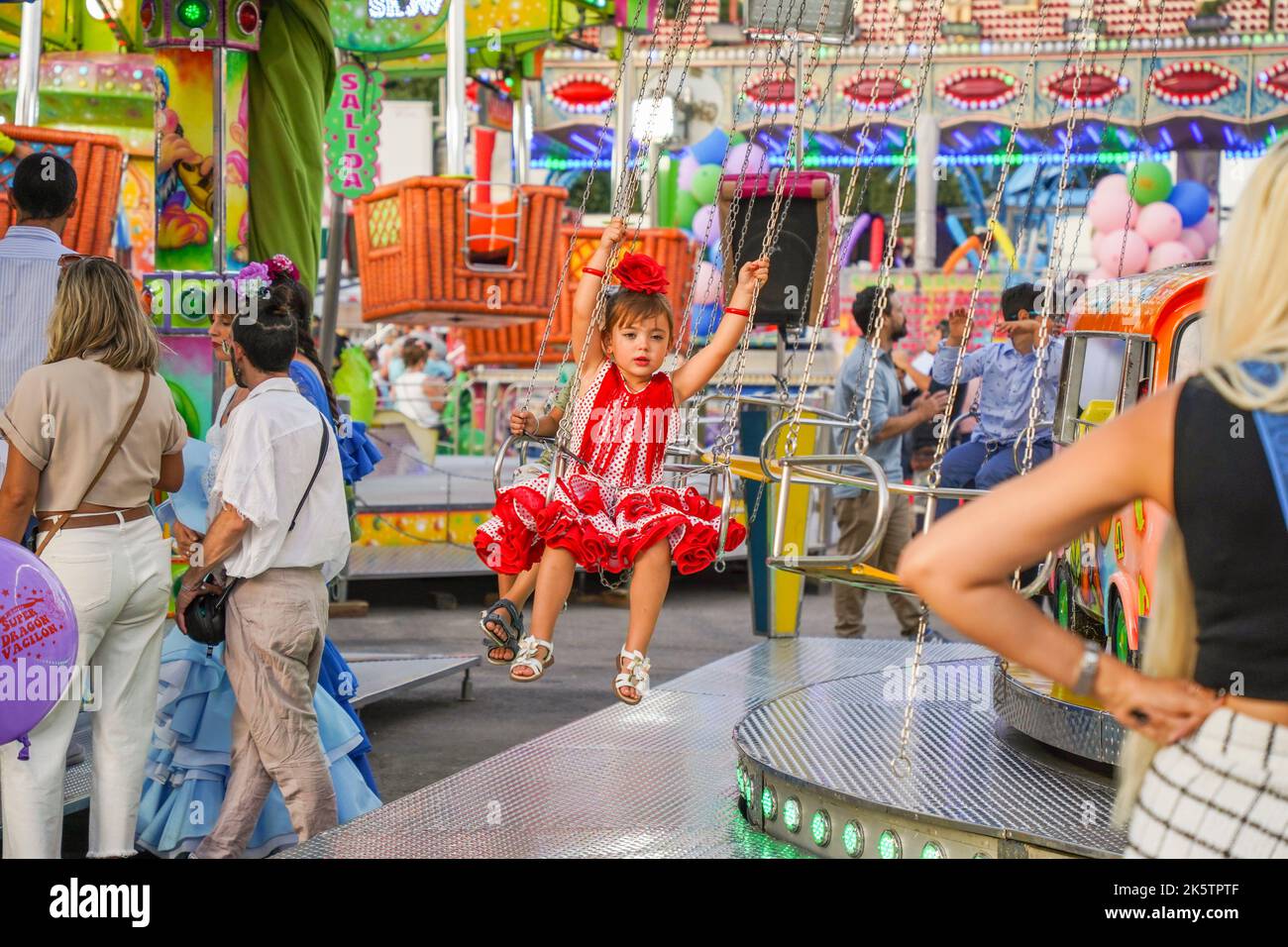 Bambina alle attrazioni del giro di divertimento su Feria annuale. fiera funebre. Carnevale, Andalusia, Spagna. Foto Stock