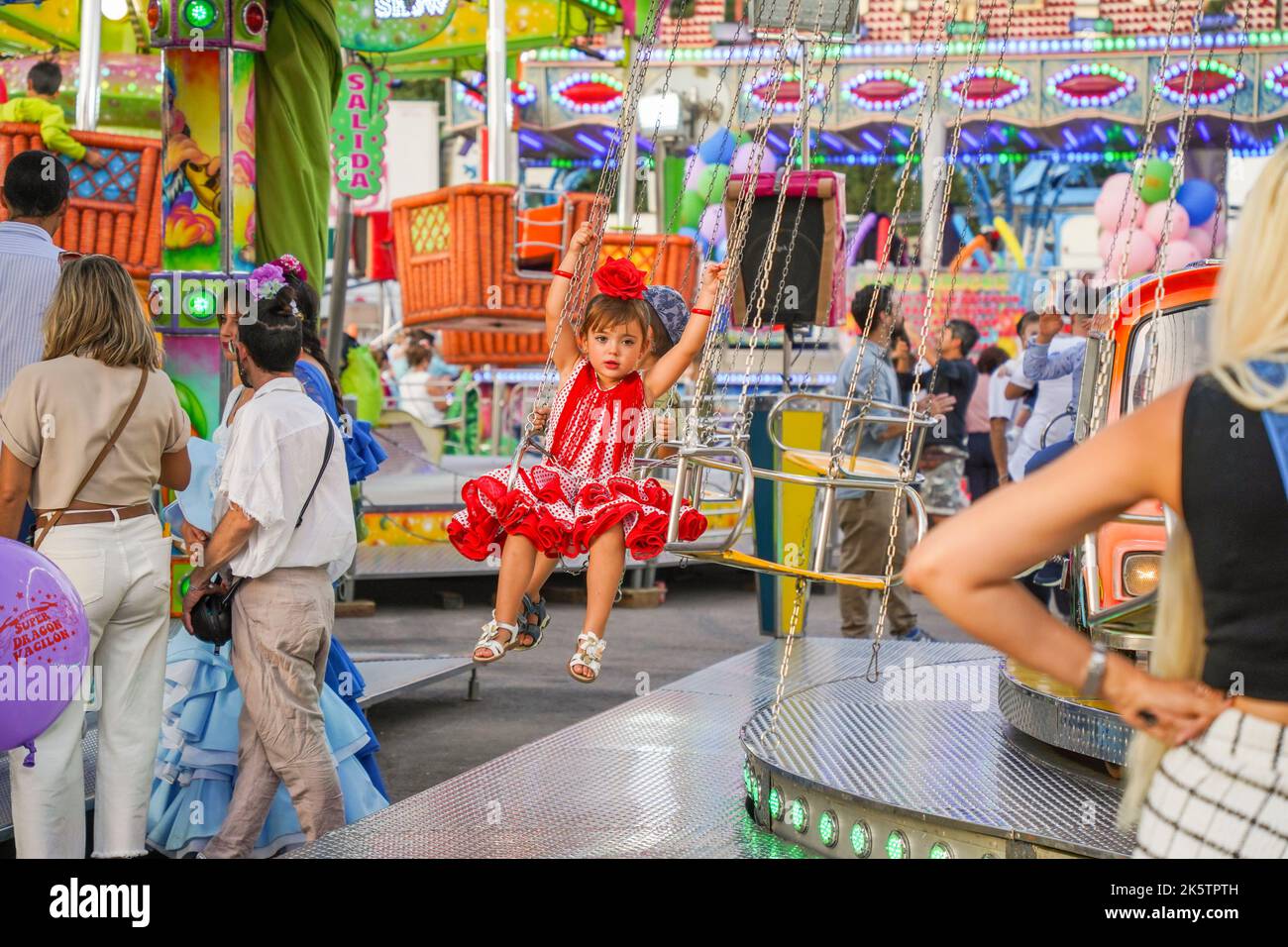 Bambina alle attrazioni del giro di divertimento su Feria annuale. fiera funebre. Carnevale, Andalusia, Spagna. Foto Stock